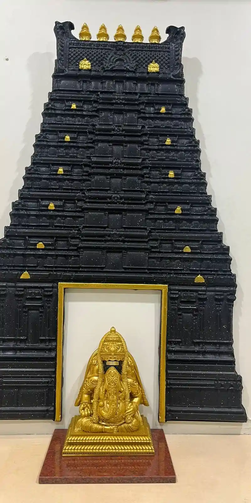 Rawdius Gopuram Customer Installation Black gopuram wall art framing a seated golden Ganesha statue on a marble pedestal