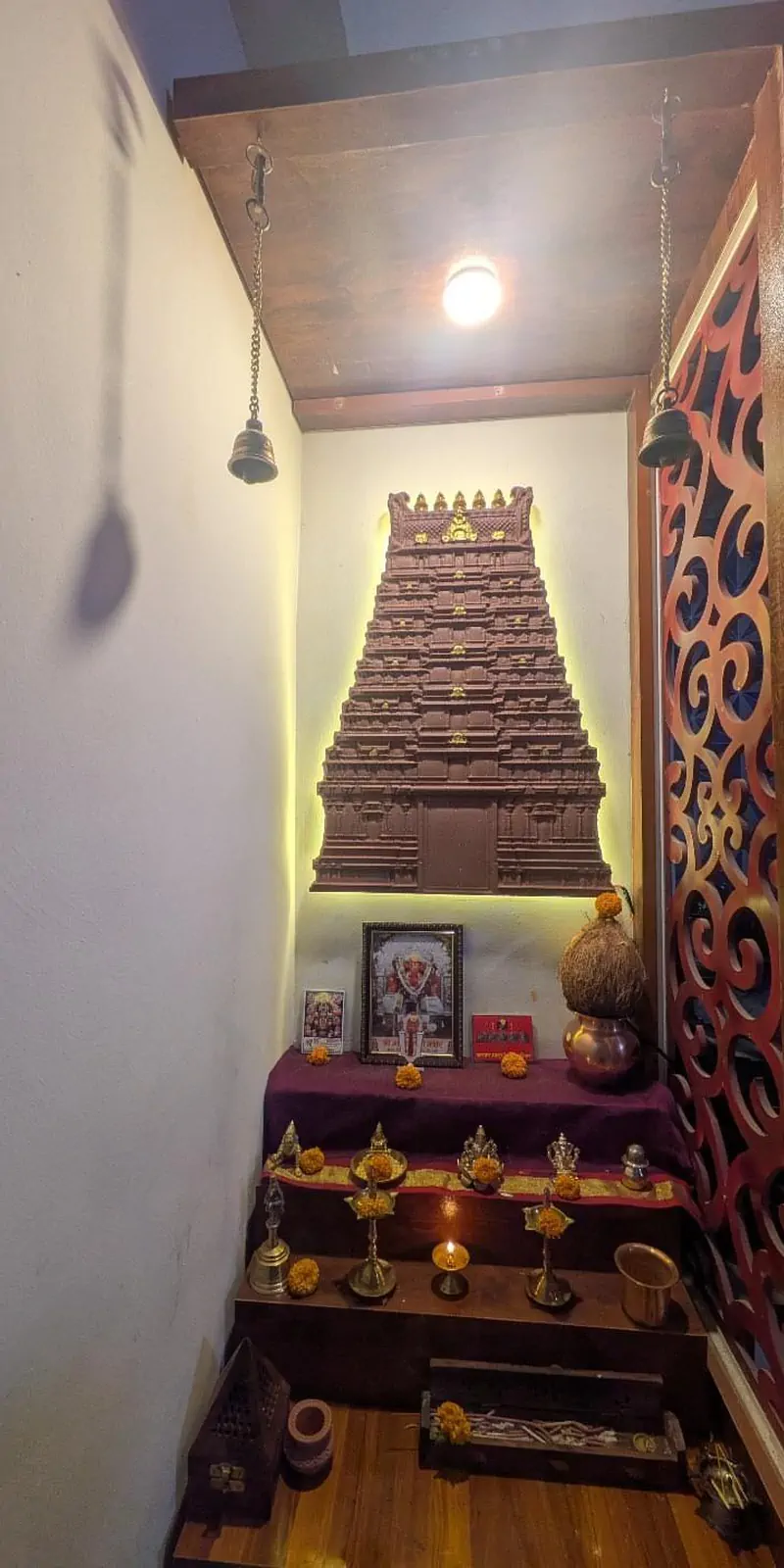 Rawdius Gopuram Customer Installation Brown backlit temple gopuram installed above a home pooja altar with brass bells