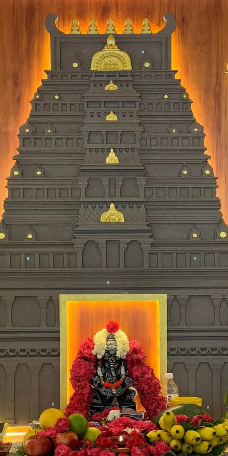 Rawdius Gopuram Customer Installation Dark grey backlit gopuram backdrop behind a garlanded Ganesha idol with pooja offerings