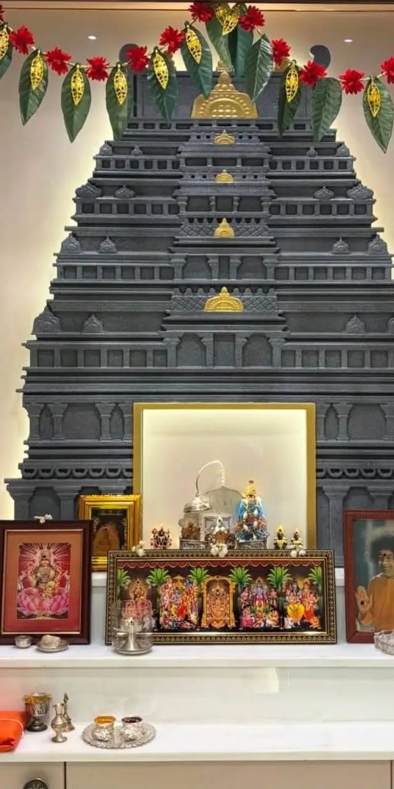 Rawdius Gopuram Customer Installation Dark grey backlit gopuram decor decorated with flower garlands above a pooja counter