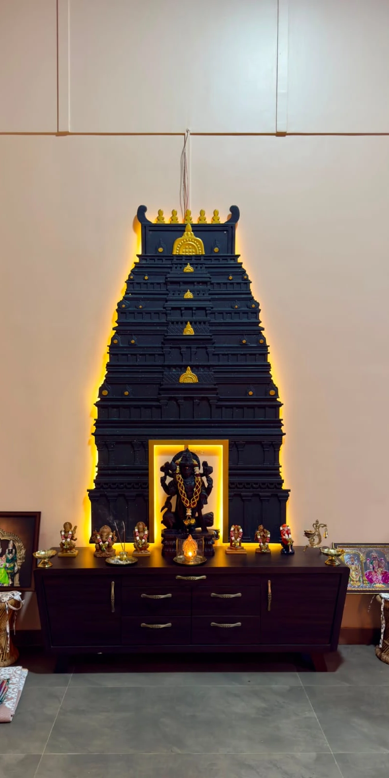 Rawdius Gopuram Customer Installation Illuminated black and gold temple gopuram wall art framing a deity statue