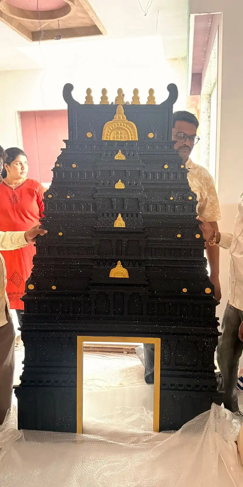 Rawdius Gopuram Customer Installation Large black and gold temple gopuram decor held by people during unboxing or assembly