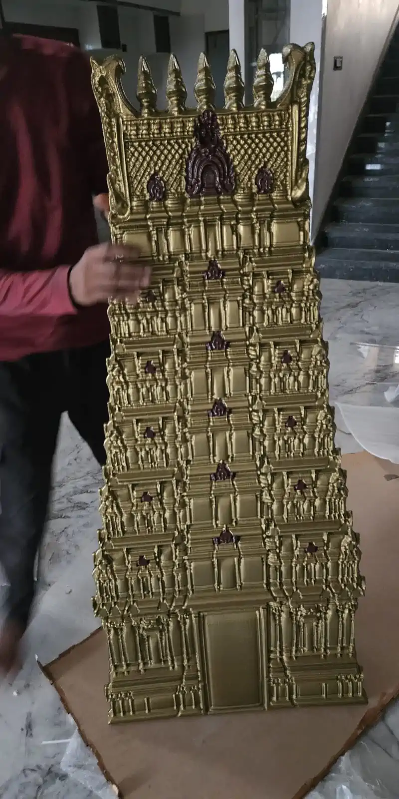 Rawdius Gopuram Customer Installation Large gold multi layer gopuram art piece held up during unpacking or installation