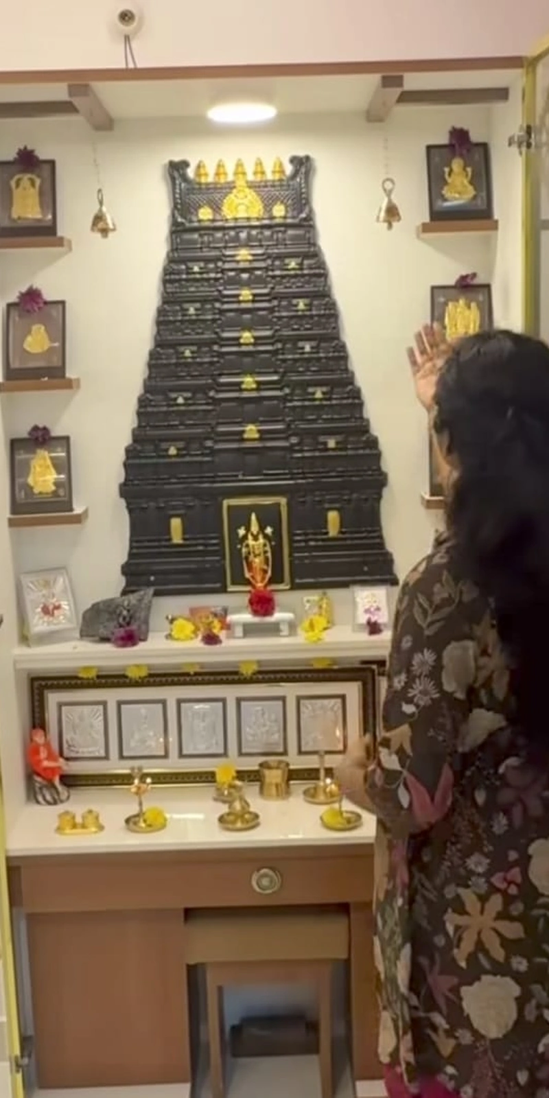 Rawdius Gopuram Customer Installation Woman praying in front of a black gopuram backdrop inside a white pooja niche