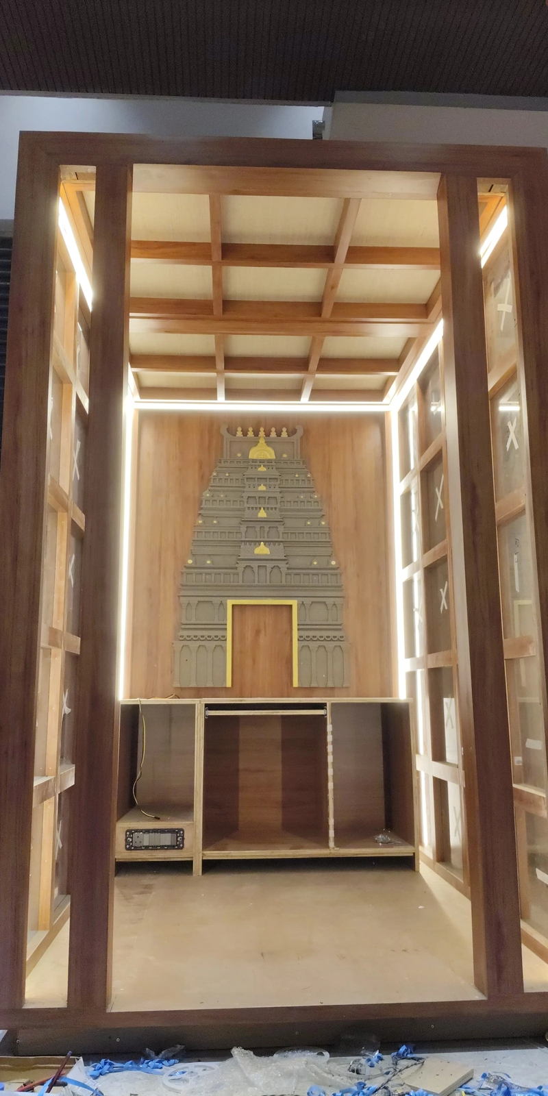 Rawdius Gopuram Customer Installation Wooden pooja room structure featuring a grey and gold temple gopuram backdrop