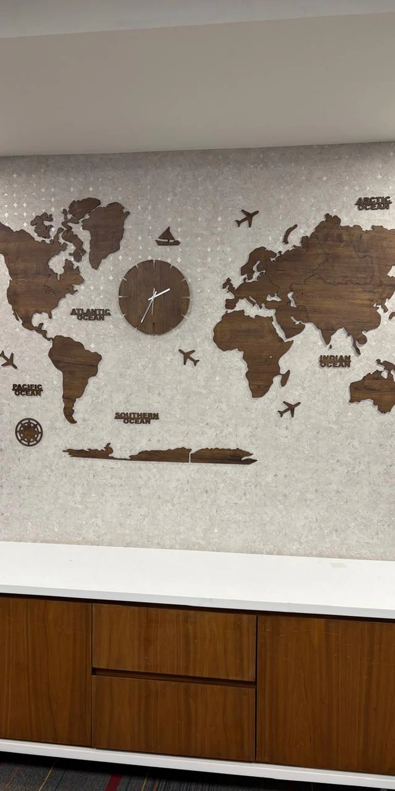 Rawdius Mirror Customer Installation 3D wooden world map with clock mounted on patterned wallpaper above cabinets
