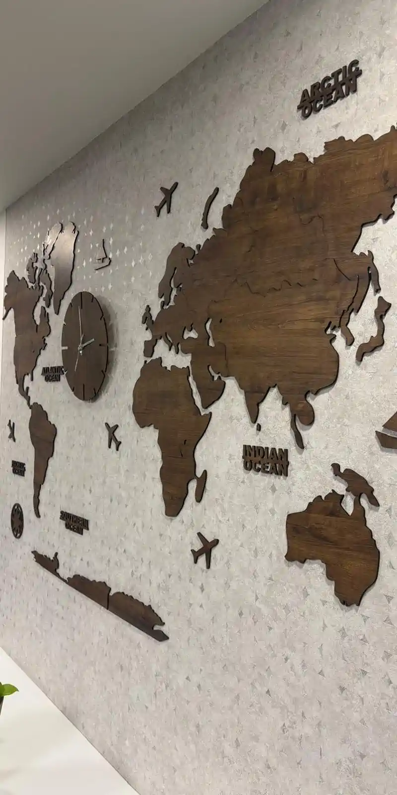 Rawdius Mirror Customer Installation Angled view of 3D layered wooden world map on a patterned wall