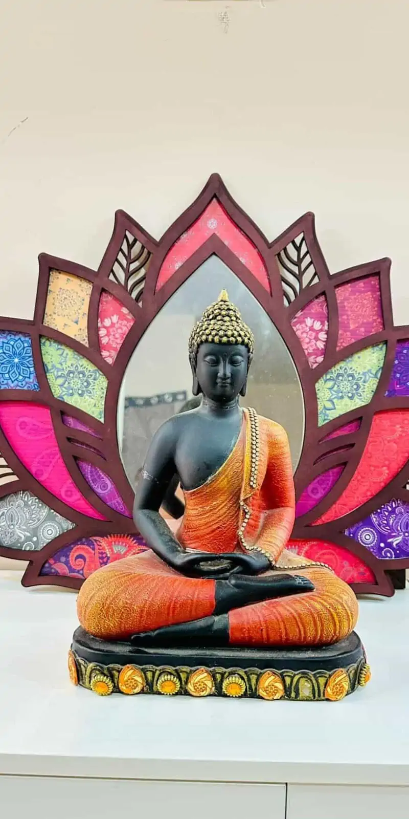 Rawdius Mirror Customer Installation Dark wooden lotus mirror with colorful patterned petal inlays behind a seated Buddha statue on a table